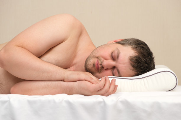 该男子侧卧着一个矫形枕头睡觉。图片下载