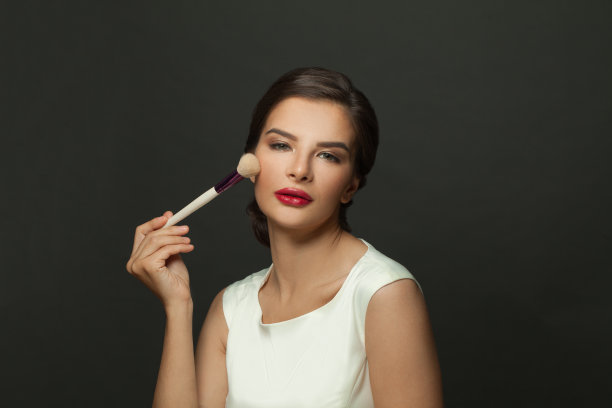 美丽的脸。用化妆刷涂抹腮红的美丽模特肖像。年轻女性，皮肤柔软光滑，妆容清新。皮肤的化妆品。图片下载