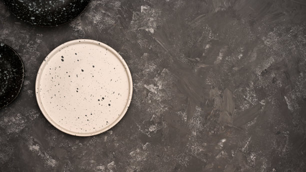 最小的餐桌背景与空白色陶瓷盘子在深灰色的背景。图片下载