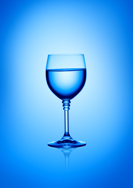 蓝色背景的一杯水。垂直的摄影。图片下载