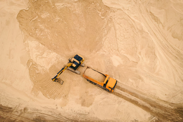 露天采石场挖掘机将砂石装进卡车图片下载