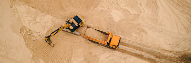 露天采石场挖掘机将砂石装进卡车图片下载