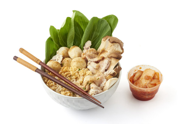 泡面放在白色的大碗里，白色的背景上放着泡菜。由方便面、调味粉、肉丸、猪肉和蔬菜组成的一碗面。受欢迎的快餐。图片下载