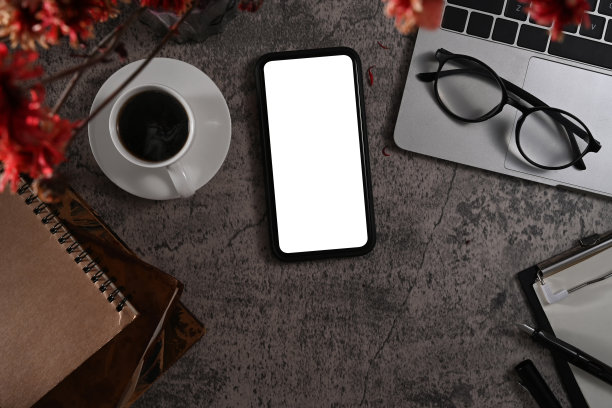 上图为空白显示的智能手机，笔记本电脑，眼镜，咖啡杯和笔记本电脑在柜石背景上。图片下载