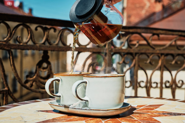 茶用玻璃茶壶倒进茶杯里，喝茶的时候，古城中心的老咖啡馆。暑假茶话会的氛围，在阳光明媚的阳台上休息放松，选择性的集中一杯图片下载