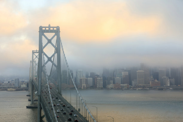 雾蒙蒙的日落在旧金山海湾大桥和海滨图片下载