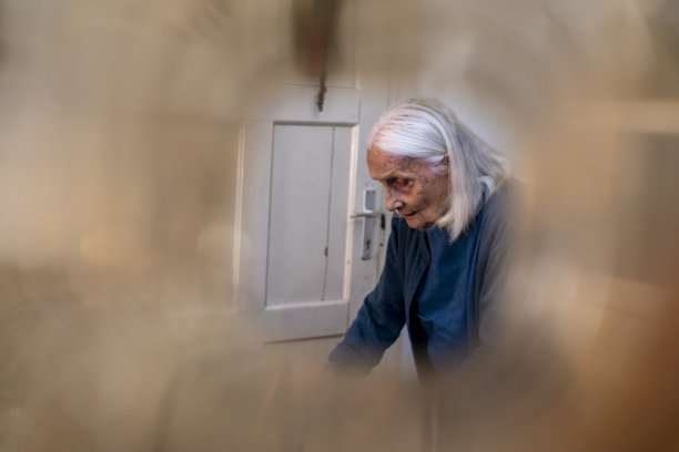 2019冠状病毒病(COVID-19)期间，老年妇女与助行器在家步行的侧视图图片下载