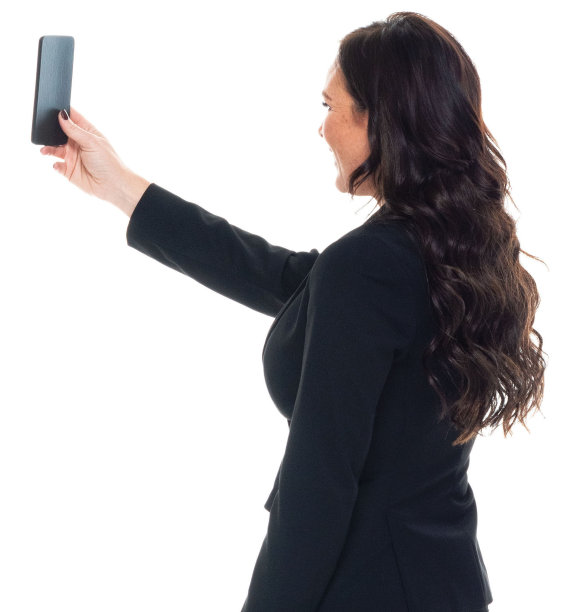 白人女性穿着职业装，用智能手机站在白色背景前拍照图片下载