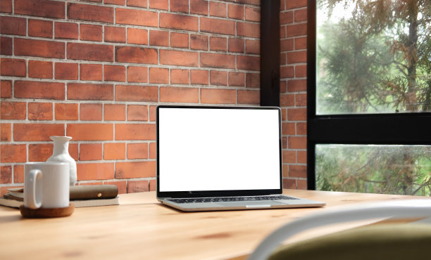 家庭办公桌，笔记本电脑，咖啡杯和书在靠近窗户的木桌。图片下载