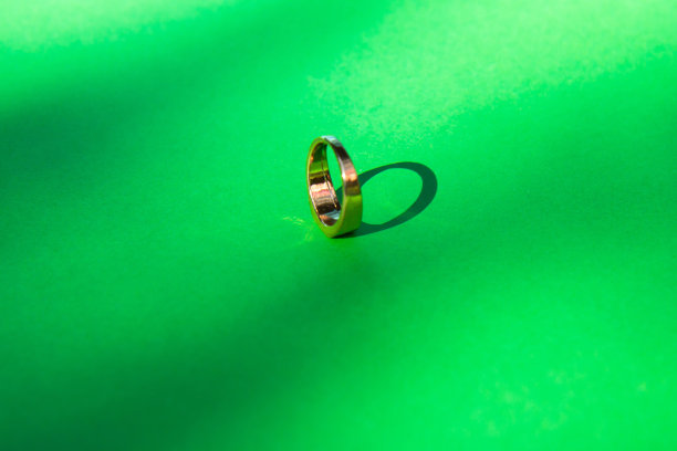 金色的结婚戒指在绿色的背景与对比阴影图片下载