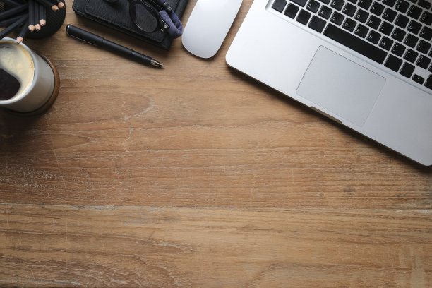 俯视图简单的工作场所与笔记本电脑，咖啡杯，眼镜和笔记本在木桌上。副本的空间。图片下载