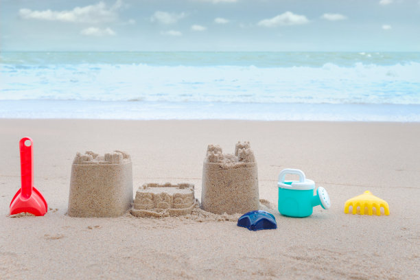 以美丽的蓝天为背景，热带夏季沙滩沙滩上的沙滩城堡和制作沙滩城堡的沙滩玩具，在海滩岛轻松的户外度假。图片下载