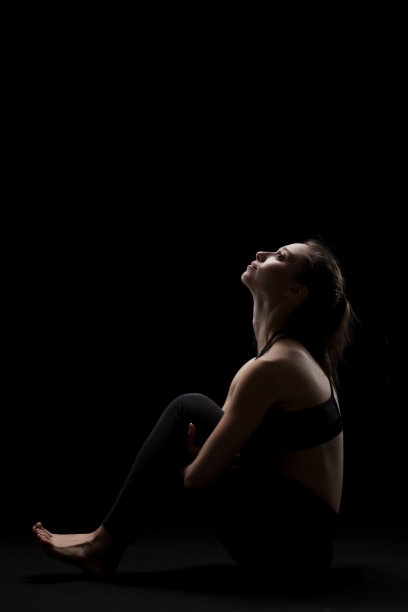 可爱的白人女孩放松瑜伽锻炼后，在黑暗的背景。侧亮轮廓。图片下载