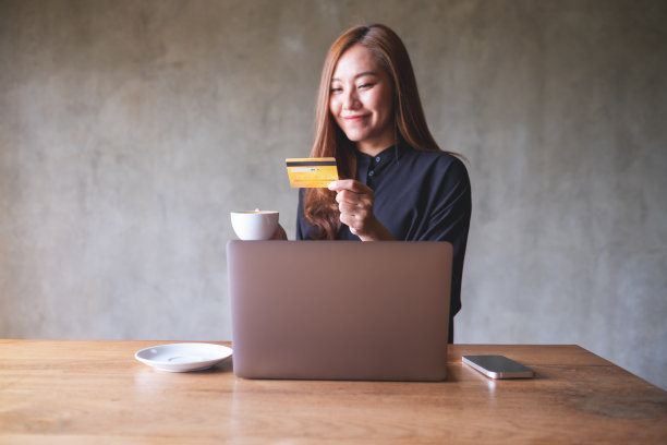 一名女商人手持咖啡杯和信用卡，使用笔记本电脑进行在线支付的画像图片下载