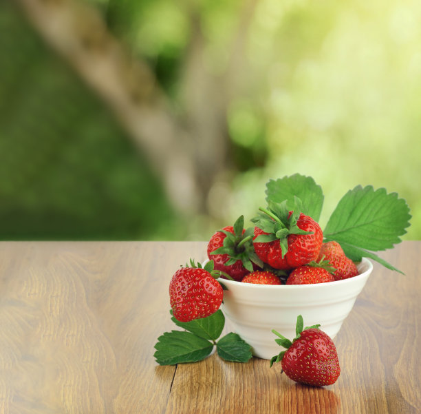 一桶刚摘的草莓在夏天的花园里。草莓放在草莓床上的桶里。图片下载
