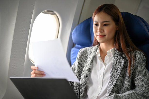 成功的亚洲女商人在飞往飞机上开会期间阅读商业报告。图片下载