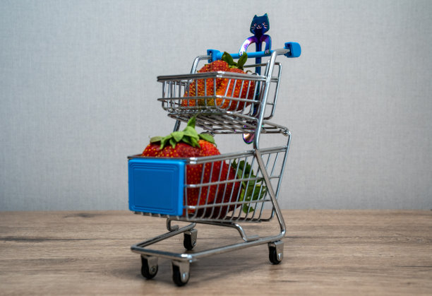 超市购物车，手推车上放着草莓，放在木桌上，概念购买的产品图片下载