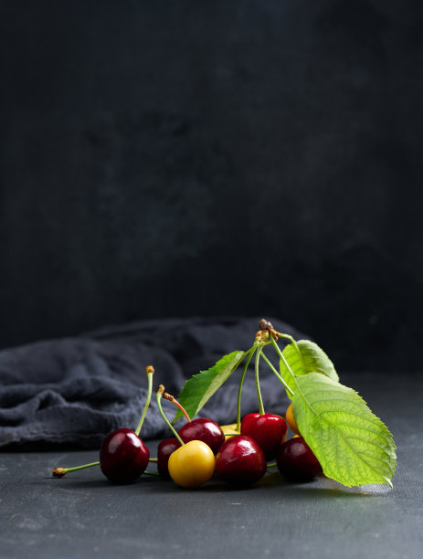 成熟的红黄樱桃在黑色的背景。夏日浆果图片下载
