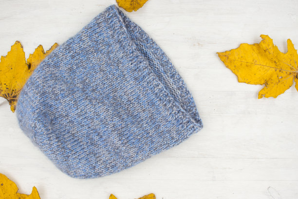 蓝色针织羊毛冬季帽子上的白色木制背景图片下载