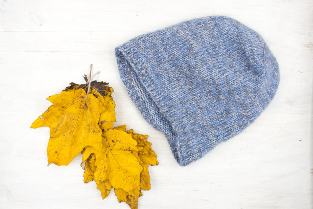 蓝色针织羊毛冬季帽子上的白色木制背景图片下载