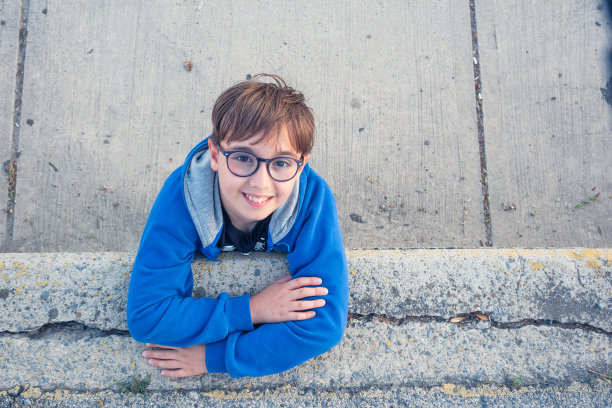 男孩靠在混凝土墙上摆姿势图片下载