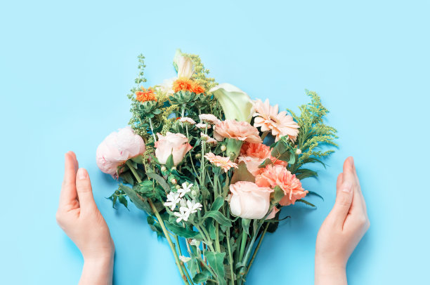 美丽的花束和女性的手在蓝色背景俯视。图片下载