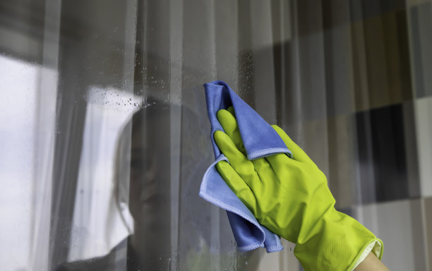 擦去窗户上的污垢。蓝色的破布。用手擦窗户。图片下载