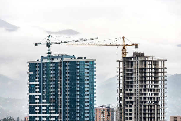 薄雾山背景下的建筑工地、起重机和多层未完工的建筑。开发建筑，建设高楼大厦公寓图片下载