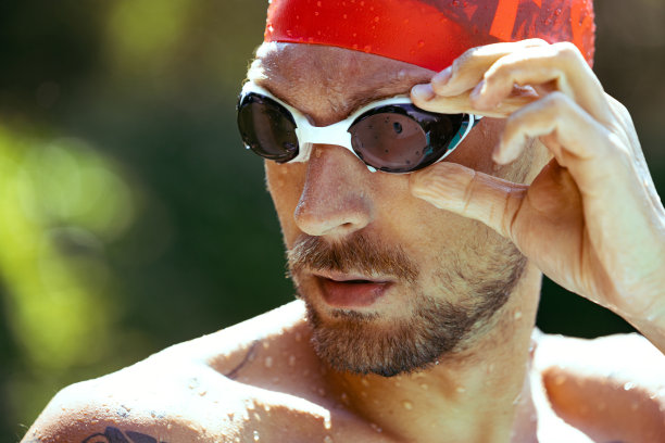 特写年轻英俊的男子，专业游泳运动员在护目镜和游泳帽准备游泳，在户外。运动，动力，能量，风格，爱好概念。图片下载