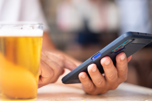 特写女性写信息时手拿手机。在左边放一杯啤酒图片下载