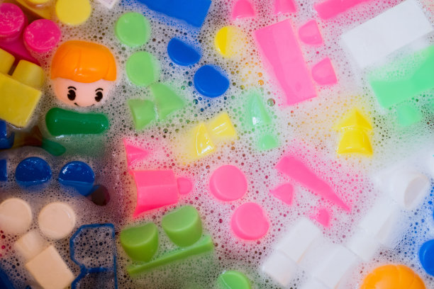 清洗儿童玩具，塑料积木和小雕像。一个微笑的小家伙和五颜六色的立方体漂浮在泡沫的水中。卫生的观念，清洁的观念。安全性和消毒图片下载