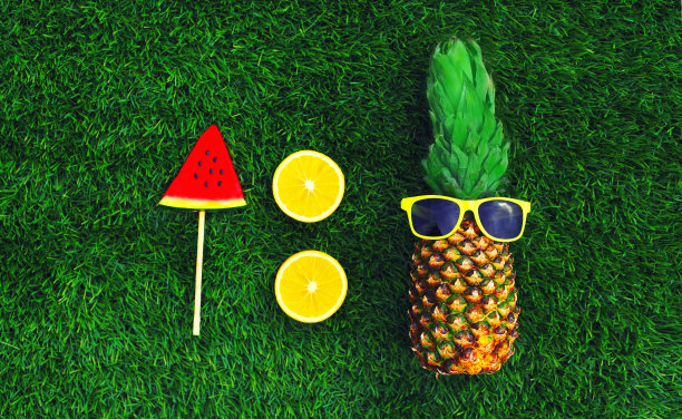 夏天新鲜的形象菠萝与太阳镜和棒棒糖或冰淇淋形状的西瓜片，橙色的草地上的背景图片下载
