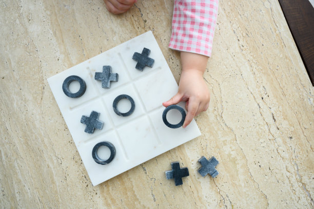 特写孩子小女孩的手在大理石桌子上玩Tic Tac Toe或OX棋盘游戏，俯视图图片下载