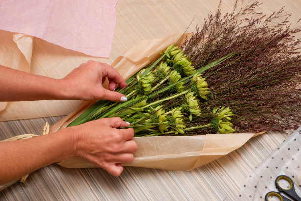 一个卖花的女孩用紫色的紫锥菊和郁郁葱葱的草制作了一个组合。特写镜头。小企业概念工作过程图片下载