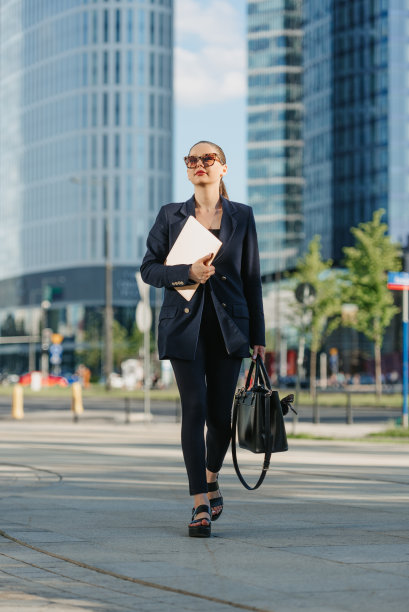 穿着西装的女房地产经纪人拿着笔记本电脑在金融区漫步图片下载