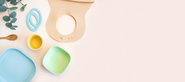 米色背景的婴儿用品和食品餐具。儿童第一喂养理念。平面布局，俯视图，文本空间。硅胶餐具，围嘴，中性背景杯。婴儿食品服务图片下载