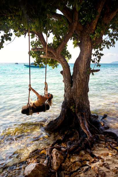 美丽的金发女人荡秋千与绳子在热带岛屿海滩图片下载