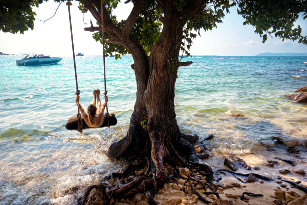 美丽的金发女人荡秋千与绳子在热带岛屿海滩图片下载