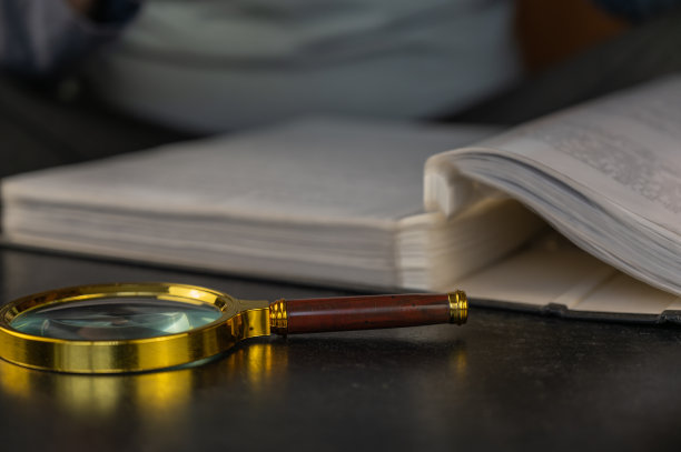 打开文件夹旁边的放大镜。黑色的桌子上放着一个金色镜框的圆形放大镜。有活页夹的灰色文件夹。特写镜头。有选择性的重点。图片下载