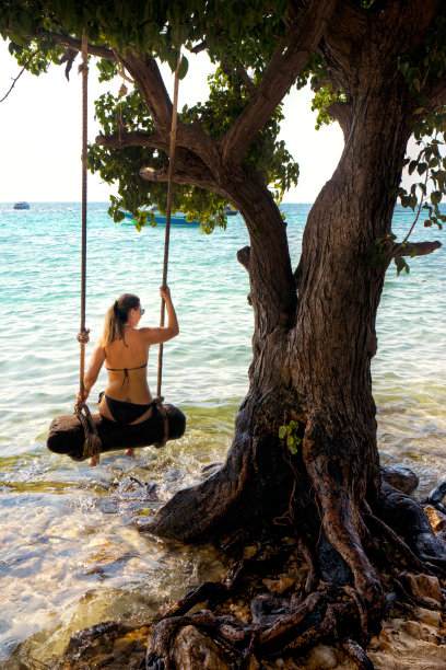 美丽的金发女人荡秋千与绳子在热带岛屿海滩图片下载