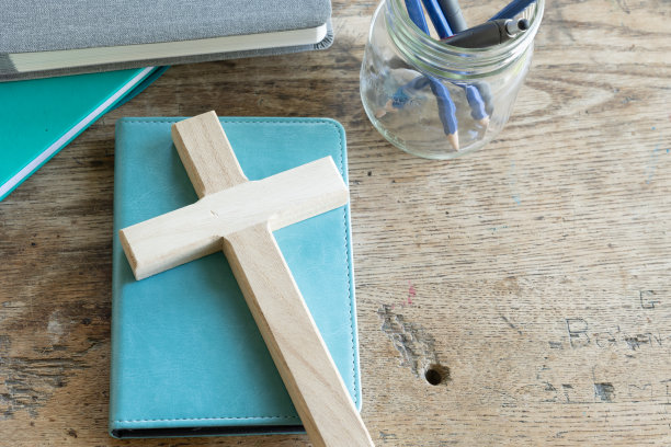 木十字架上的蓝绿色书在古董木书桌图片下载