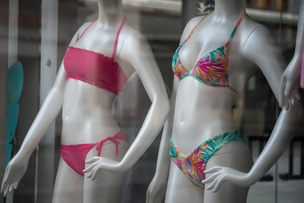 在时装商店陈列室里，穿着橙色和粉色比基尼的模特图片下载
