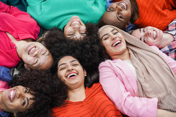 一群多种族女性朋友有乐趣躺在公园的草地上-关注阿拉伯女孩的脸图片下载