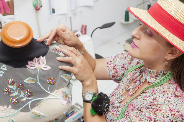 富有创意的女时装设计师仔细地看着黑色的纺织材料的人体模型图片下载