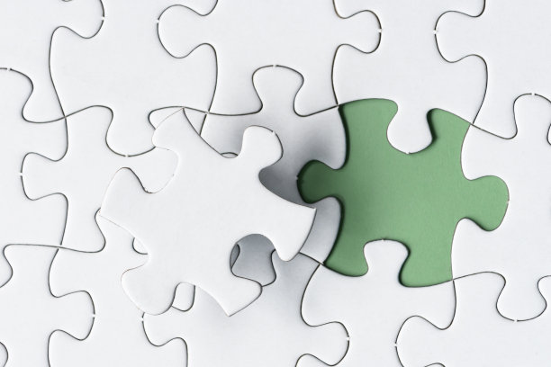 绿色背景上缺一块的白色拼图。副本的空间。图片下载