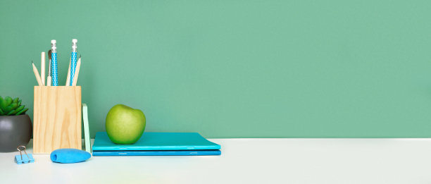 学校设备上白色的桌子，绿色的墙壁背景。教育背景。木制的学校用品，笔记本，铅笔和仙人掌植物。回到学校。学生的桌子上。文具进行研究。在家里工作图片下载