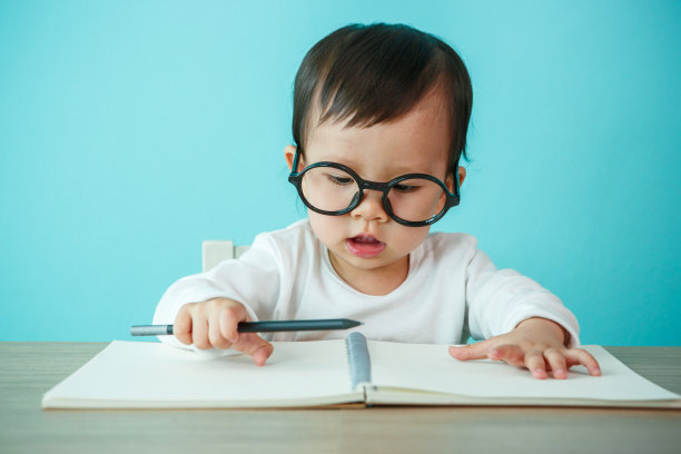 新生儿微笑着戴着眼镜，放在桌子上(温柔地注视着眼睛)图片下载