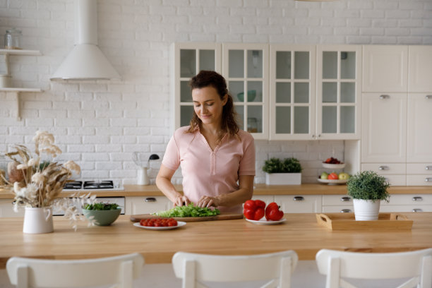 快乐的女房主在自家厨房切蔬菜做沙拉图片下载