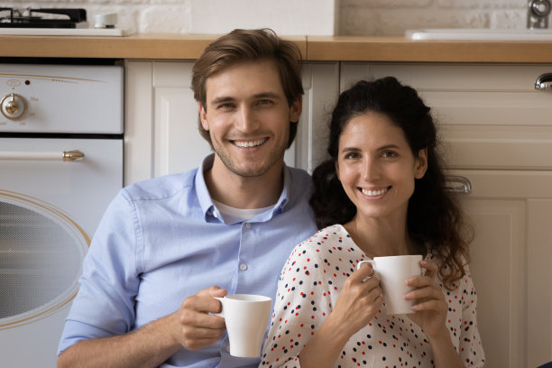 微笑的年轻夫妇手持茶杯的肖像。图片下载