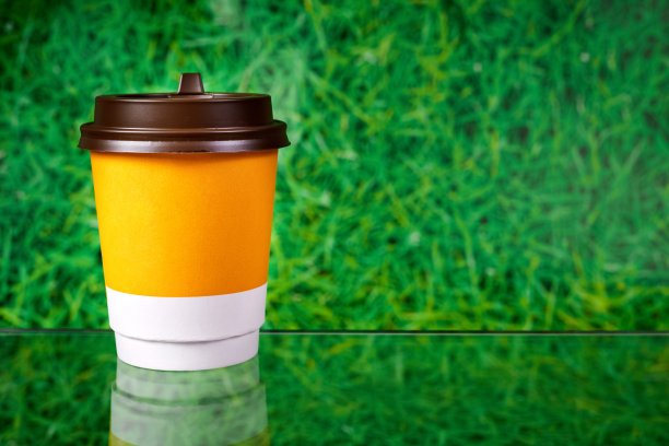 外带的饮料杯放在木制的表面，背景是绿色的草地图片下载